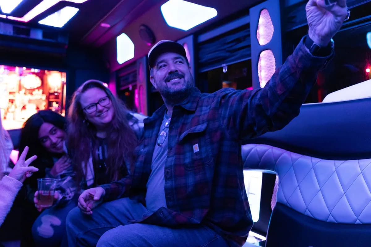 Friends celebrating inside a party bus with purple LED lighting and quilted leather seats — a BYOB party bus night in Illinois