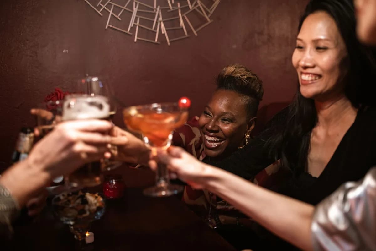 Laughing friends clinking cocktail glasses at a bar during a Chicago bar crawl