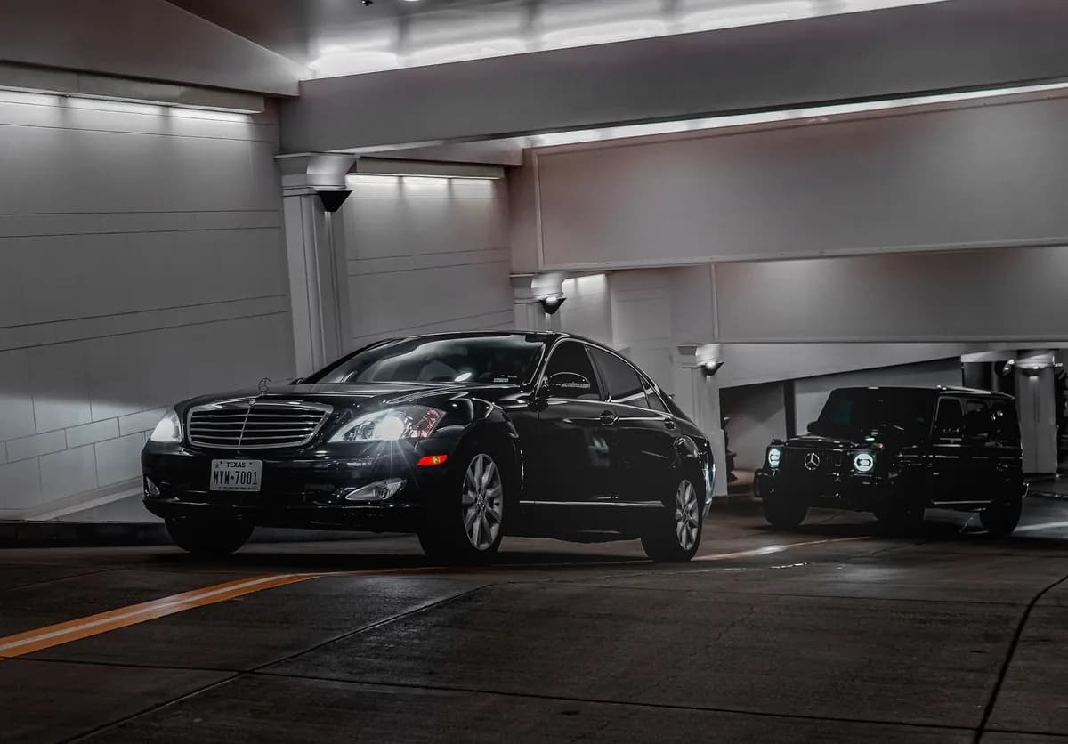 A black luxury sedan in front of a black SUV in an urban tunnel — choosing between a sedan and an SUV for a Chicago airport transfer