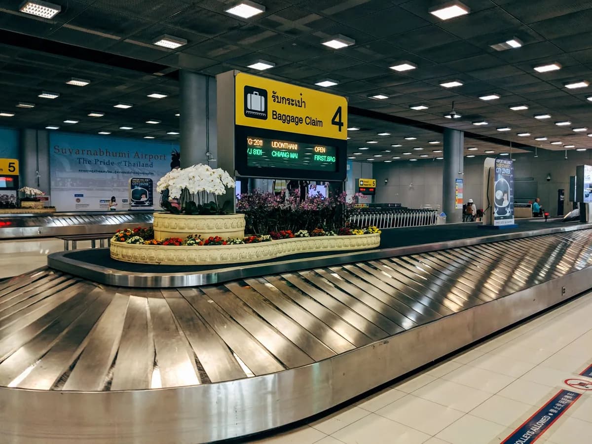 Airport baggage-claim carousel with an illuminated baggage-claim sign and flight screens — where a chauffeur meets international arrivals at O'Hare