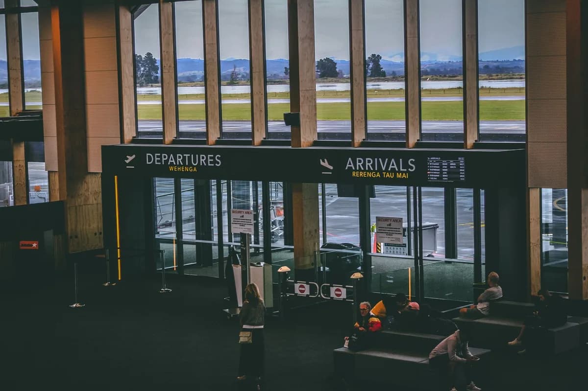 Airport terminal interior with prominent Departures and Arrivals signage — the arrivals area where a meet-and-greet chauffeur greets you versus curbside pickup